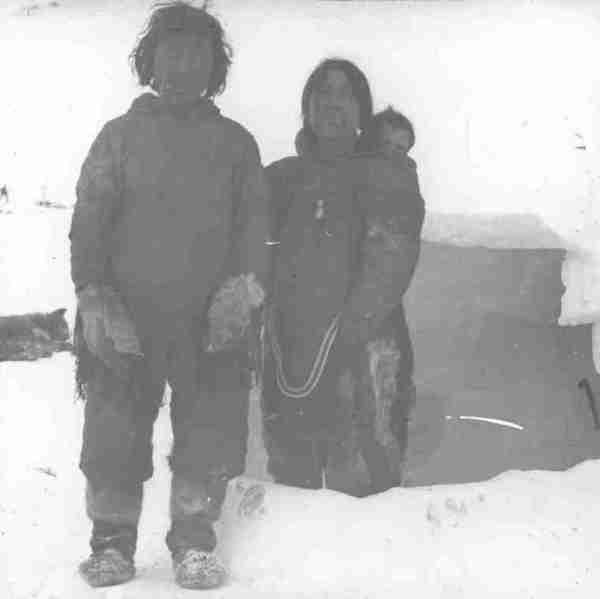 Inuit family at entrance to igloo.
